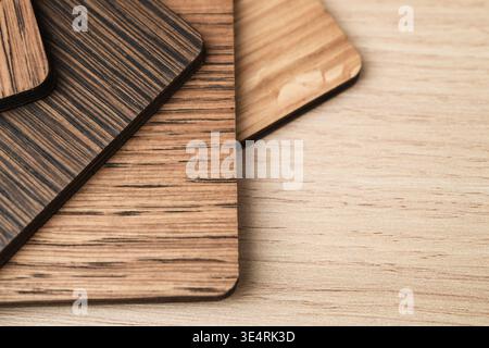 Varnished wooden samples with rounded corners lie on a light wood surface, showing different grain patterns and finishes in a close-up view. Stock Photo