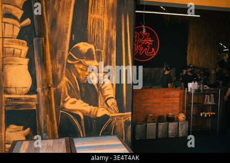 Vibrant mural of a potter alongside a neon-lit urban cafe interior with staff and brick details. Stock Photo