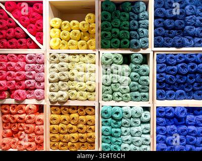 Balls of wool of many colours neatly arranged and on sale in a haberdashery shop, stored in a storage unit divided into cubes Stock Photo