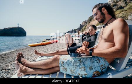 Beach, Laptop, Work - Man Uses Laptop on Beach with Woman Stock Photo
