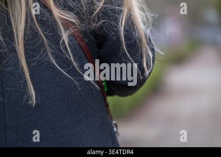 Close up of an anonymous woman walking outdoors with long hair and casual clothing. Scene represents everyday lifestyle, movement, and urban or park e Stock Photo
