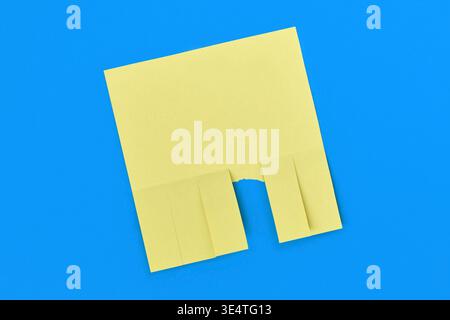 Yellow tear off flyer with multiple detachable tabs and one strip torn away on blue background. Blank notice template for advertisements or contact te Stock Photo