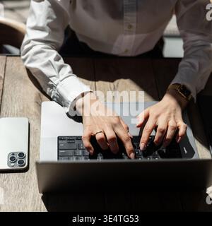 Close-up of female hands typing on a laptop keyboard with stylish accessories nearby. Business and technology concept. Stock Photo