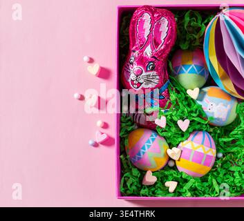 Decorated Easter Eggs with Chocolate Bunny and Marshmallow Hearts on Pink Background Stock Photo