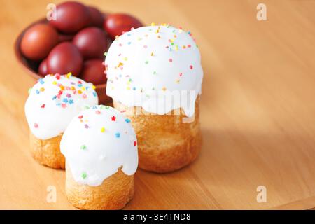 Traditional Orthodox Easter cakes with white frosting and red eggs on a rustic wooden table, bright spring holiday still life. Stock Photo