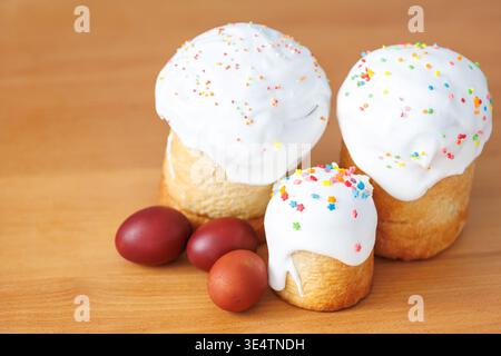 Group of Easter cakes and painted red eggs on a wooden board, minimalist spring celebration concept with copy space. Stock Photo