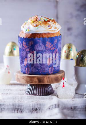 Easter cake, chocolate eggs in gold foil and chicken-shaped candles on a light background. Stock Photo