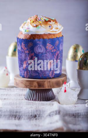 Easter cake, chocolate eggs in gold foil and chicken-shaped candles on a light background. Stock Photo
