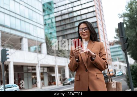 Professional woman using smartphone in modern city street Stock Photo
