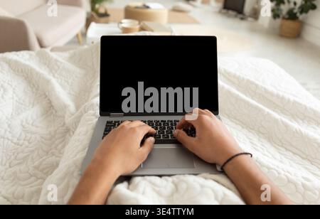 Cropped Shot Of Man Using Laptop Working Lying In Bedroom Stock Photo