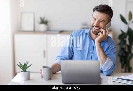 Smiling Man Office Employee Talking On Cellphone And Drinking Coffee At Workplace Stock Photo