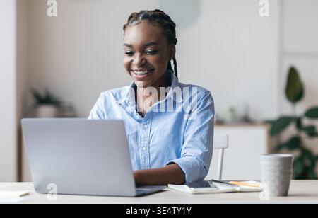 Young Black Secretary Working On Laptop In Modern Office, Typing On Keyboard Stock Photo