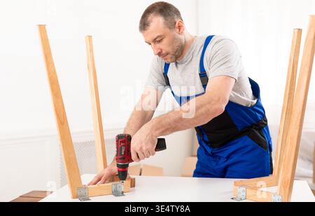 Man Carpenter Using Electric Drill Assembling Wooden Table Stock Photo