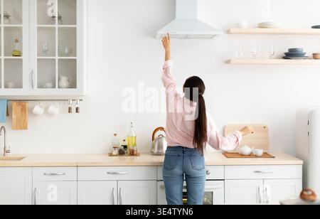 Woman select mode on cooking hood in kitchen Stock Photo