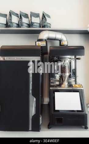 Industrial coffee roasting machine with bean chamber and blank touchscreen mockup, modern professional equipment in cafe interior, ideal for branding, Stock Photo