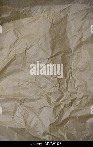 Crumpled paper background. High-angle shot of a Wrinkled and creased beige paper surface. Ideal for rustic backgrounds, vintage overlays, recycling co Stock Photo
