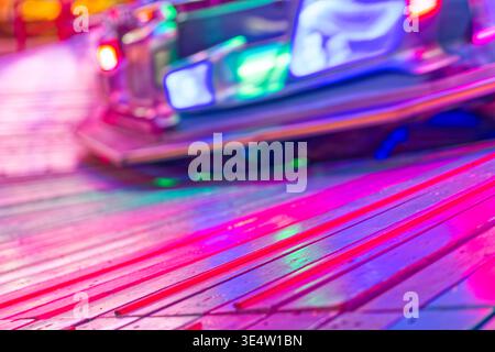 Vibrant neon lights in pink blue and green hues reflecting on a polished wooden floor creating a colorful and dynamic atmosphere with a blurred backgr Stock Photo