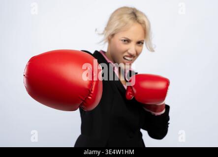 Woman in Business Suit Practices Boxing With Red Gloves for Fitness and Empowerment Stock Photo