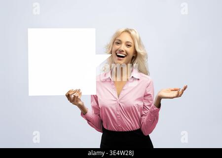 Woman Holding Blank Speech Bubble in Studio While Smiling and Gesturing With Her Hand Stock Photo