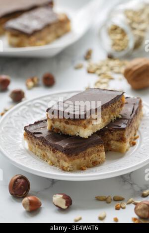 Food, Homemade Vegan cocoa dates chocolate bars with coconut, hazelnuts, walnuts and sunflower seeds on a white background. Healthy dessert. The conce Stock Photo