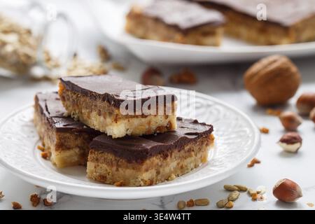 Food, Homemade Vegan cocoa dates chocolate bars with coconut, hazelnuts, walnuts and sunflower seeds on a white background. Healthy dessert. The conce Stock Photo