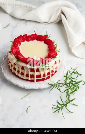 Food, Homemade red velvet cake with white chocolate, fresh strawberries and rosemary. Delicious gourmet dessert in a white plate on a marble surface c Stock Photo