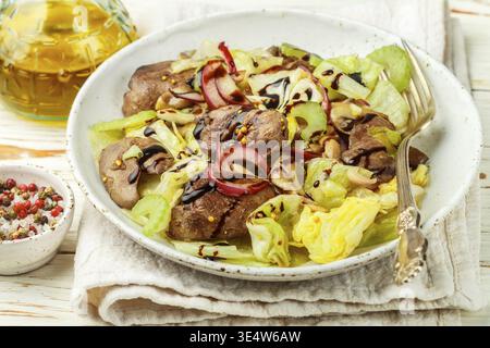Food, Warm salad of chicken (duck, goose, rabbit) liver, iceberg lettuce, red onion, celery and fried mushrooms with dressing of olive oil, balsamic a Stock Photo