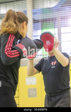 Boxing training with a woman hitting handguards under guidance in a sports hall, boxing TSV Calw, Germany Stock Photo