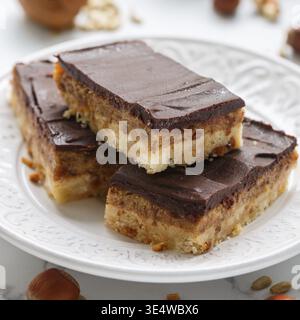 Food, Homemade Vegan cocoa dates chocolate bars with coconut, hazelnuts, walnuts and sunflower seeds on a white background. Healthy dessert. The conce Stock Photo