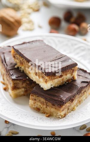 Food, Homemade Vegan cocoa dates chocolate bars with coconut, hazelnuts, walnuts and sunflower seeds on a white background. Healthy dessert. The conce Stock Photo