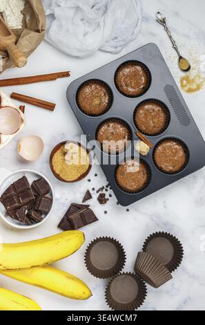 Food, Preparation homemade muffins with banana and chocolate for Breakfast. Ingredients on the table - wheat flour, eggs, brown sugar, chocolate chips Stock Photo