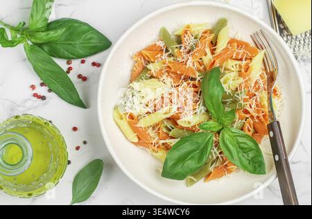 Food, Tricolor pasta. Multicolored Penne (wheat, spinach, tomato) in a white plate with cheese, Basil and olive oil. Delicious Mediterranean dinner. S Stock Photo