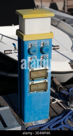 Marina power pedestal with sockets for boats on dock Stock Photo