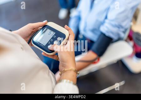 Pharmacist monitoring patient blood pressure using digital sphygmomanometer Stock Photo