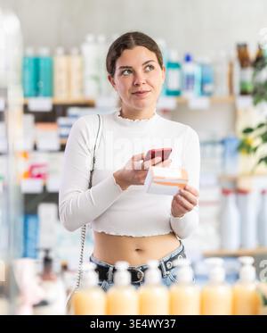 woman scans a package of pills with a mobile barcode in front of a counter in a pharmacy Stock Photo