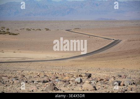 Winding road through desert landscape in Death Valley National Park, California, USA, with mountains in the background. Stock Photo