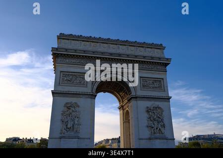 Majestic low-angle view of the Arc de Triomphe in Paris at dusk under a clear blue sky Stock Photo