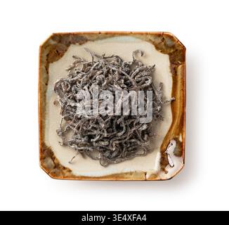 Salted kelp (Shiokombu) on a small ceramic plate isolated on white background, Top view Stock Photo