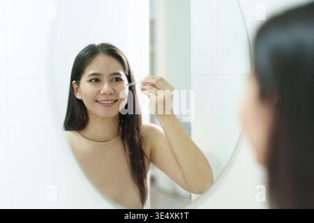 Woman applying makeup in front of a mirror Stock Photo