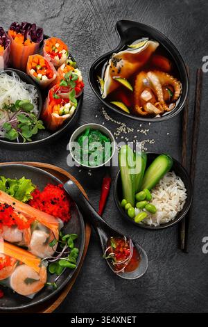 Various vietnamese spring rolls filled with various fresh ingredients such as vegetables, spices, meat or shrimps on a dark background. Top view. Stock Photo