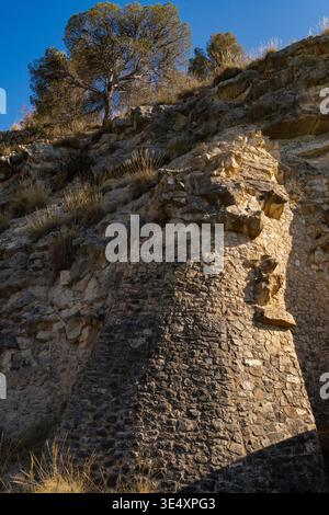 A massive stone retaining wall built directly into a limestone cliff at the Amadorio Reservoir in Alicante. Spain. The traditional stonework features Stock Photo
