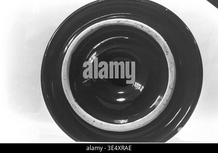 Sloviansk, 1960s, Armature-Insulator Plant (AIZ) - A close-up view focusing on the base of a defective ceramic electrical insulator. The archival image highlights the unglazed circular mounting ring and distinct flaws in the application of the dark industrial glaze. This detailed macro photograph documents the strict quality control challenges and material realities of mid-century Soviet porcelain manufacturing, capturing the authentic history of heavy industry and energy sector production in the peaceful Donbas. Stock Photo