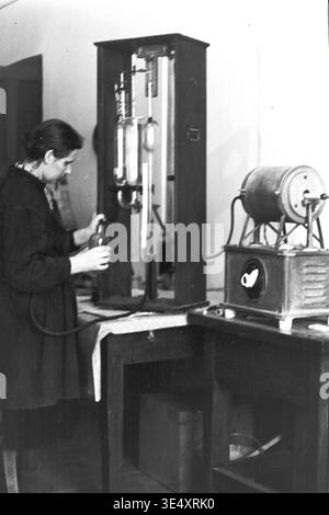 Sloviansk, 1950s-1960s, Armature-Insulator Plant (AIZ) - A focused female laboratory technician carefully operates complex analytical glassware and a small electric muffle furnace within the factory's testing facility. Engaged in rigorous chemical or material quality control, she exemplifies the scientific precision required in mid-century Soviet porcelain production. This authentic archival photograph honors the crucial role of women in science and heavy industry development in the peaceful Donbas. Stock Photo