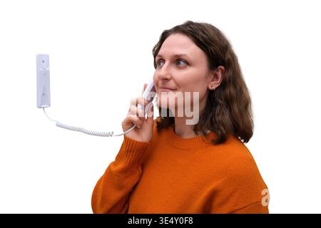 Woman using white wall intercom system. woman talking on wired telephone handset. Communication, security and access control device. Modern building e Stock Photo