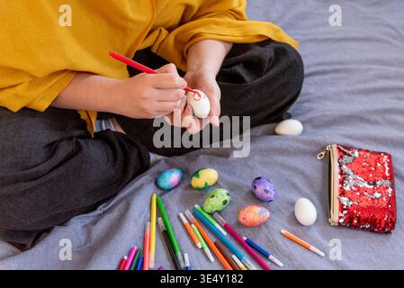 Woman decorating white eggs with colored felt-tip pens, traditional decoration for Easter holiday Stock Photo