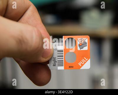 Paris, France - Jan 13, 2026: Close up of hand holding printer setup sticker with pull instruction and barcode in office environment with blurred back Stock Photo