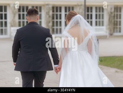 Wedding couple walking together outdoors after ceremony. Romantic moment of love, partnership, and new beginning. Elegant and natural wedding scene. Stock Photo