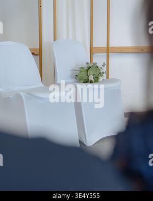 Wedding ceremony setup with white chairs and minimal decor. Clean and elegant interior for event, celebration, or formal occasion. Stock Photo
