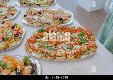 Assorted canapes with tomatoes and greens on catering trays. Light and fresh finger food for buffet, party, or corporate event. Clean and appetizing Stock Photo