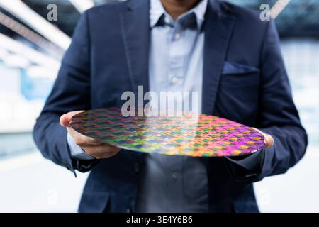 Looking at semiconductor substrate, microelectronic closeup and manager in microchip factory. Analyzing automated machines production yield, silicon wafers and expert in industrial manufacturing plant Stock Photo
